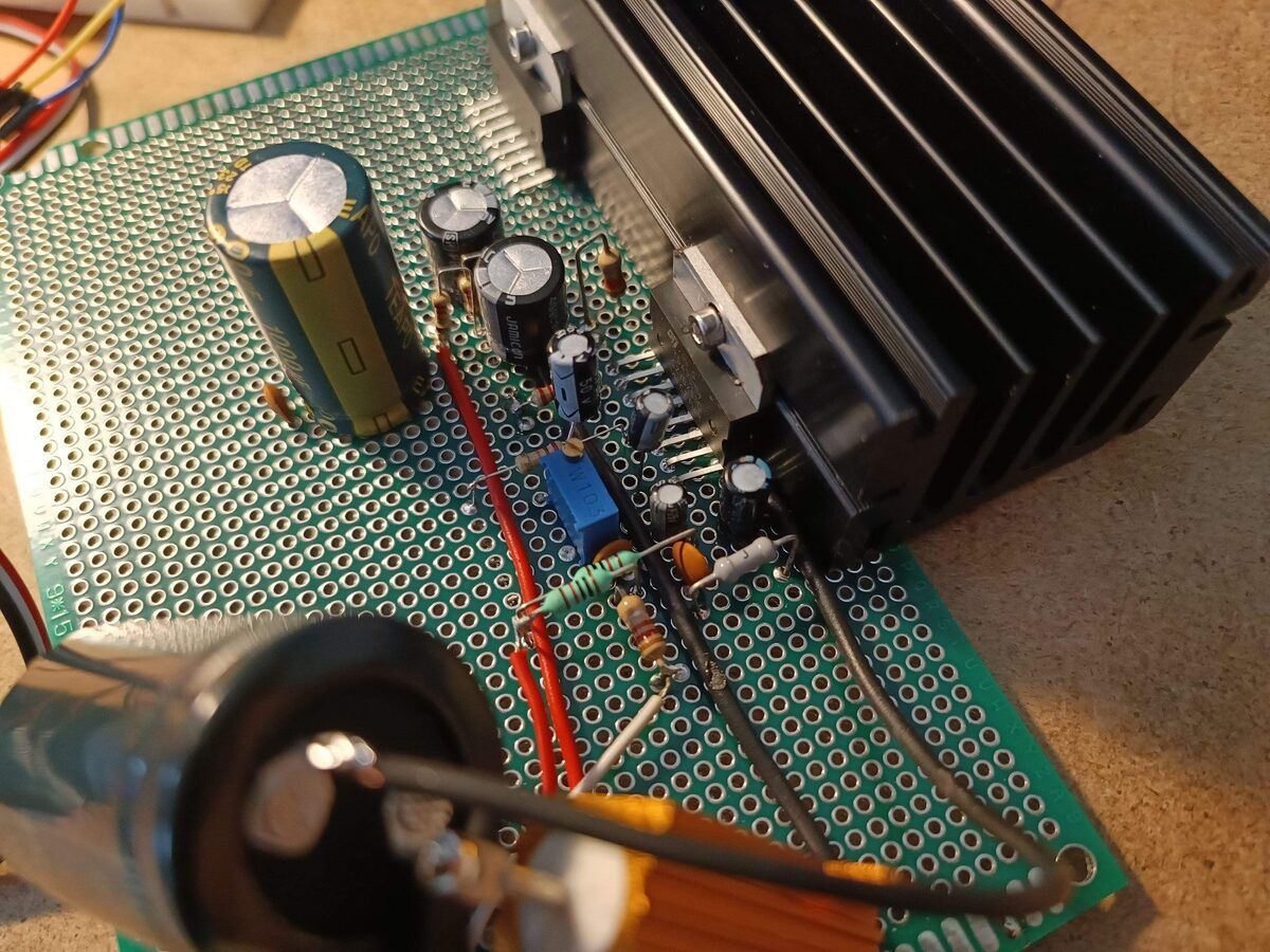 Close-up of the perfboard: rail bulk capacitor, level trimmer, input network, Zobel and feedback parts around the TDA7294